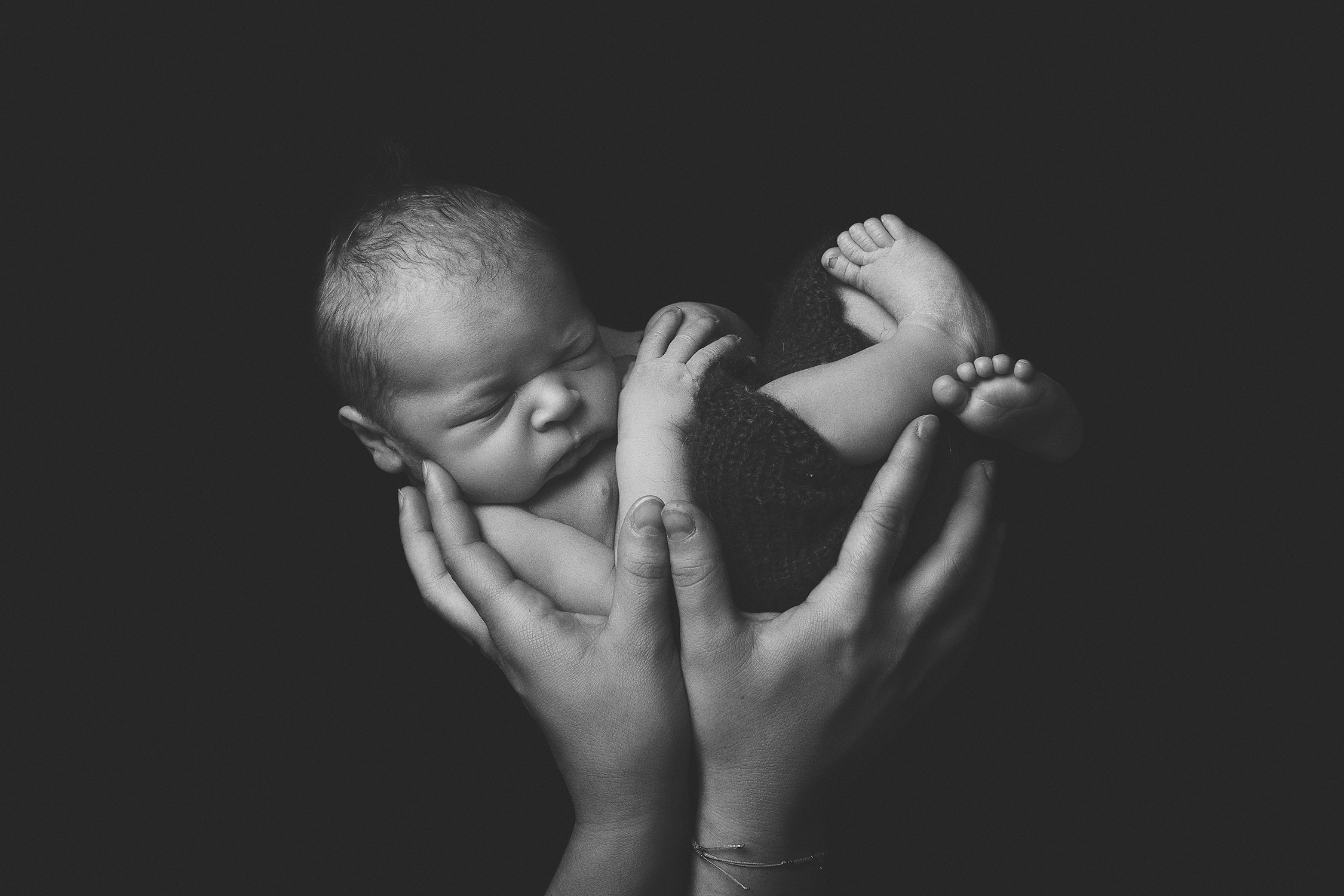 nouveau-né dans les mains de sa maman en noir et blanc
